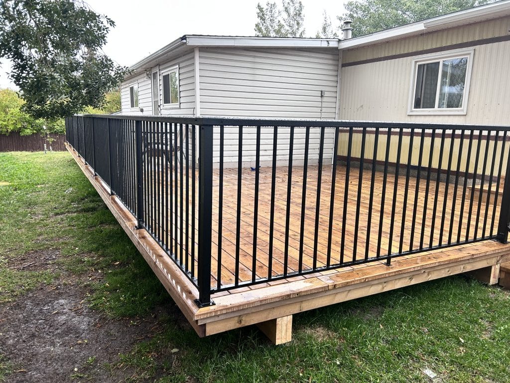 Pressure treated wood deck with black aluminum railing built by Pemadale in Airdrie Alberta